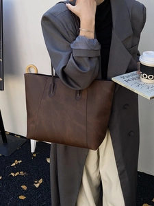 Close-up of vintage brown leather tote bag with vertical stitching for casual commute