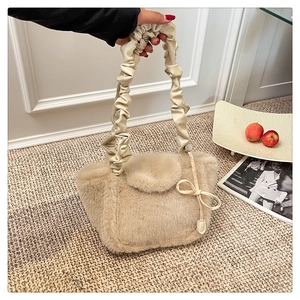 Detail of soft faux fur handbag featuring scrunchie handle and cute bow charm