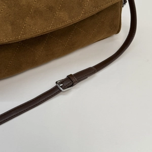Detail of brown suede shoulder bag with quilted diamond pattern and adjustable leather strap