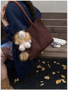 Detail einer braunen geflochtenen Tragetasche mit Plüschtieranhänger im Herbst-Look