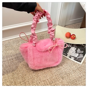 Detail of pink plush faux fur handbag featuring soft ruched handles and decorative bow knot