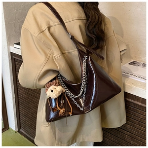 Close-up of brown glossy crescent hobo bag with silver chains and bear charm