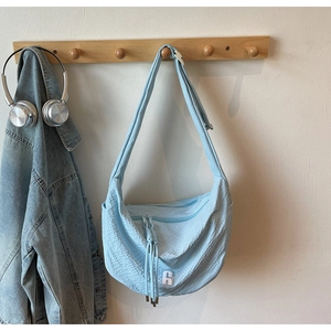 Detail of light blue crescent bag with waffle texture and white letter R patch on a hook