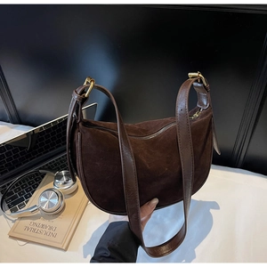 Detail view of brown suede dumpling bag with leather strap and gold metal buckle