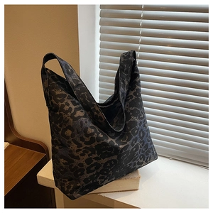 Detail view of large leopard print tote bag placed on books in soft indoor lighting