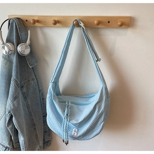 Detail view of light blue hobo bag showing crinkled texture fabric and zipper pull cord