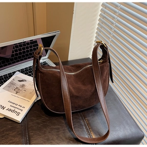 Detailed close-up of dark brown suede hobo bag with adjustable strap in workplace setting