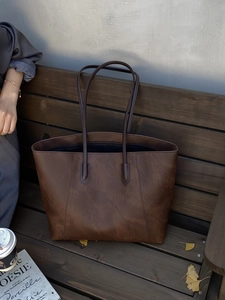 Detail of vintage brown leather tote bag on wooden bench with autumn lifestyle props