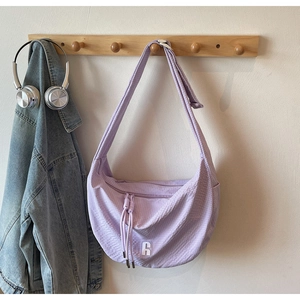 Detail of light purple dumpling bag with waffle texture and wide shoulder strap