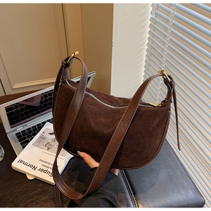 Detail of suede crescent hobo bag with leather trim and adjustable gold hardware buckle
