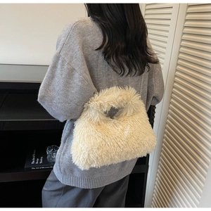 Detail der cremefarbenen Kunstfell-Handtasche mit feiner Metallkette als Schultergurt