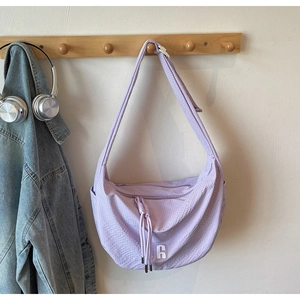Detail of purple waffle texture crossbody bag with drawstring on a wooden hanger