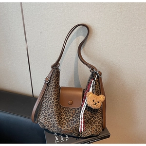 Detail of leopard print hobo bag with brown leather trim and cute teddy bear charm