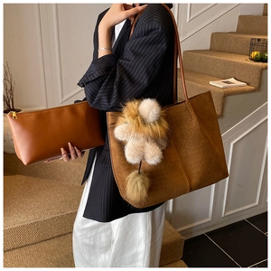 Detail der braunen gewebten Tragetasche und Clutch mit dekorativem Bommel-Anhänger