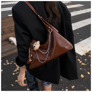 Detail of brown leather hobo bag with silver chain and leopard print plush bear charm