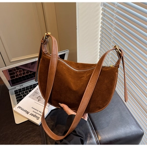 Detail of a brown suede half-moon bag with leather strap and golden hardware