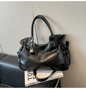 Detail einer schwarzen Ledertasche mit silbernen Sternen und Schleifenanhänger auf Sofa