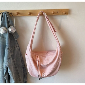 Detailed texture of pink waffle-knit shoulder bag hanging with stylish R-logo tag