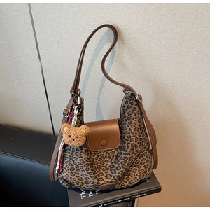 Detail of leopard print tote bag with brown leather flap and cute plush bear keychain