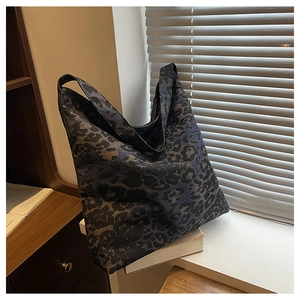 Detail view of large leopard print tote bag with wide shoulder strap on wooden background