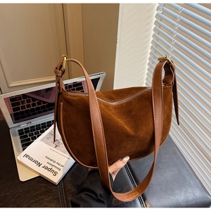 Close-up of brown suede dumpling bag with leather strap and golden zipper detail