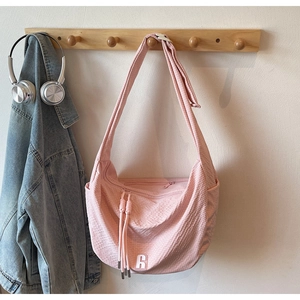 Detail of pink woven hobo bag showing R logo and side pocket on wooden hanger