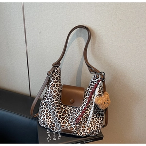 Detail of leopard print tote bag with brown leather flap and cute plush bear charm