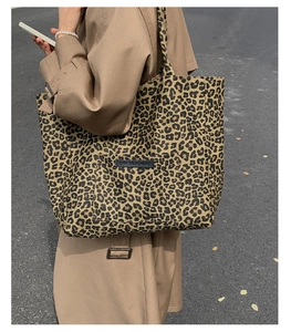 Detail view of leopard print tote bag with pocket and OWN THE MOMENT leather patch