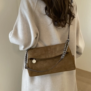 Close-up of brown suede crossbody bag with quilted diamond pattern and chain strap