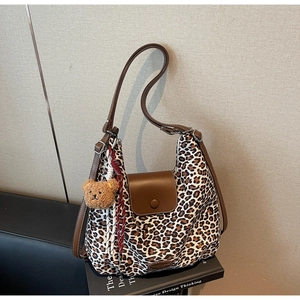 Detailed close-up of leopard print tote bag with brown leather flap and cute bear pendant