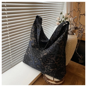 Detail of large leopard print tote bag with rich blue and black tones on wooden stand