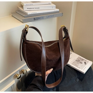 Detail of dark brown suede crescent bag featuring leather trim and gold metal hardware