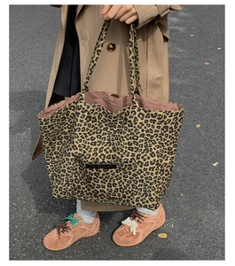 Street style shot of a leopard print tote bag featuring a front pocket and logo patch