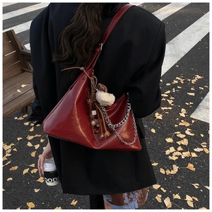 Detail of burgundy PU leather hobo bag with silver chain and plush sheep charm decoration