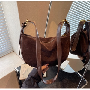 Detail of dark brown suede hobo bag featuring smooth leather strap and gold hardware accents