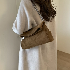 Close-up of brown suede quilted shoulder bag with silver chain and beige wool coat