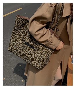 Close-up of leopard print tote bag with black Enjoy the Moment label in outdoor setting