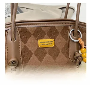 Detail of brown suede tote with diamond quilting, gold logo plate and wooden beads