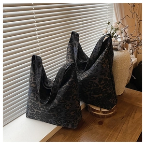 Close-up of two dark leopard print tote bags on a wooden table with natural light