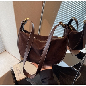 Detail of dark brown suede crescent bag with adjustable strap and metal buckle