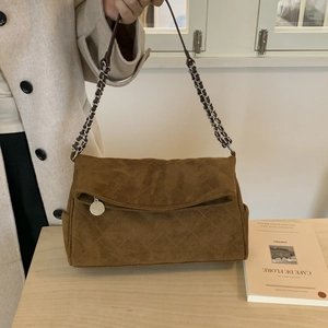 Detailed view of brown suede crossbody bag with quilted stitching and gold chain strap