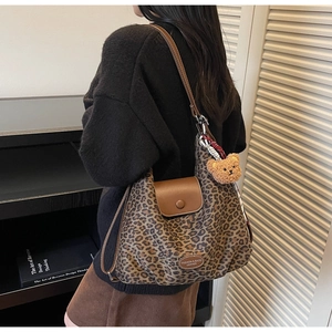 Close-up of leopard print hobo bag featuring a brown leather flap and a cute teddy charm