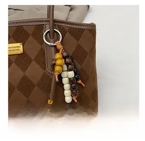 Detail of bohemian wood bead charm with silver ring on brown quilted bag strap