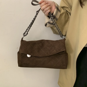 Macro view of dark brown quilted suede shoulder bag featuring silver chain strap detail