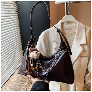 Detail of dark brown wax leather handbag with silver chain and cute plush dog charm
