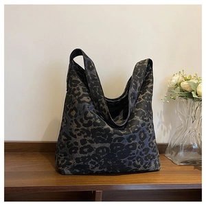 Detailed close-up of dark leopard print canvas tote bag on a wooden display stand