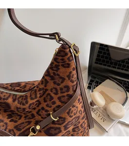 Close-up of leopard print suede tote bag with golden hardware and adjustable brown leather strap