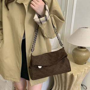 Detail of suede quilted chain bag in coffee brown worn with a chic autumn trench coat