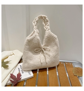 Detailed close-up of cream knit handbag featuring a bow accent and braided handle texture