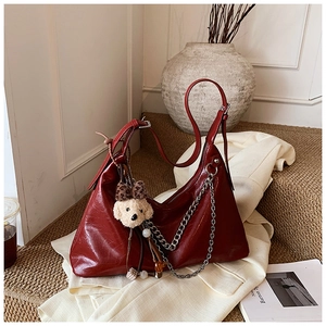 Detail of burgundy leather shoulder bag with silver chain and cute brown bear charm